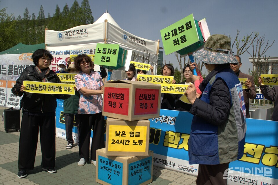 간병노동자들이 21일 국회 앞에서 산재보험 적용과 노동자성 인정을 촉구하며 차별 구조를 상징하는 상자를 부수는 퍼포먼스를 하고 있다. ⓒ투데이신문<br>